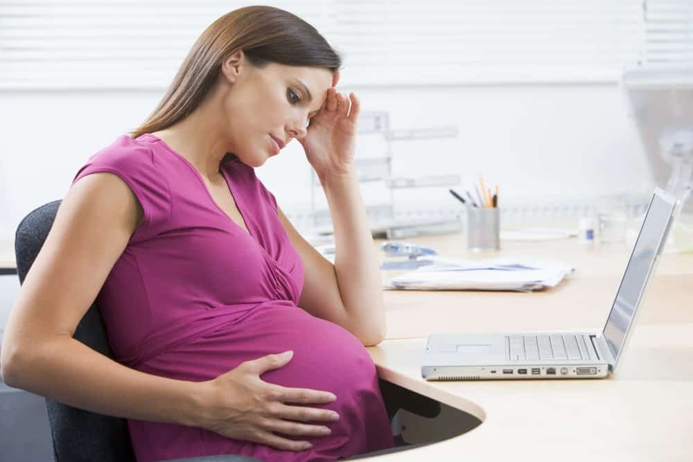 A pregnant woman consults a maternity rights solicitor in an office, discussing her legal rights and protections.