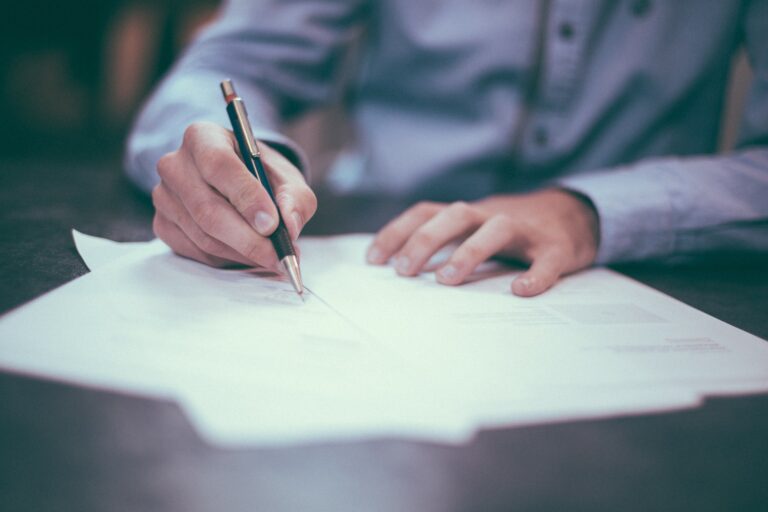 Man signing a settlement agreement document with a solicitor present, symbolising legal expertise in settlements.