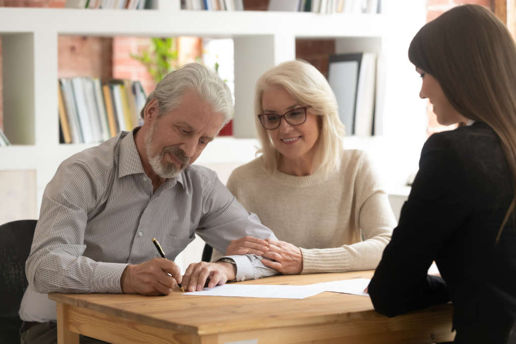 Elderly couple signing a will with a solicitor, discussing wills and probate services.