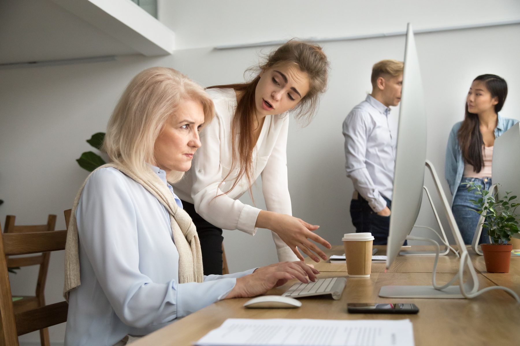 An office setting with an employee appearing uncomfortable as a colleague stands too close, symbolising workplace harassment.